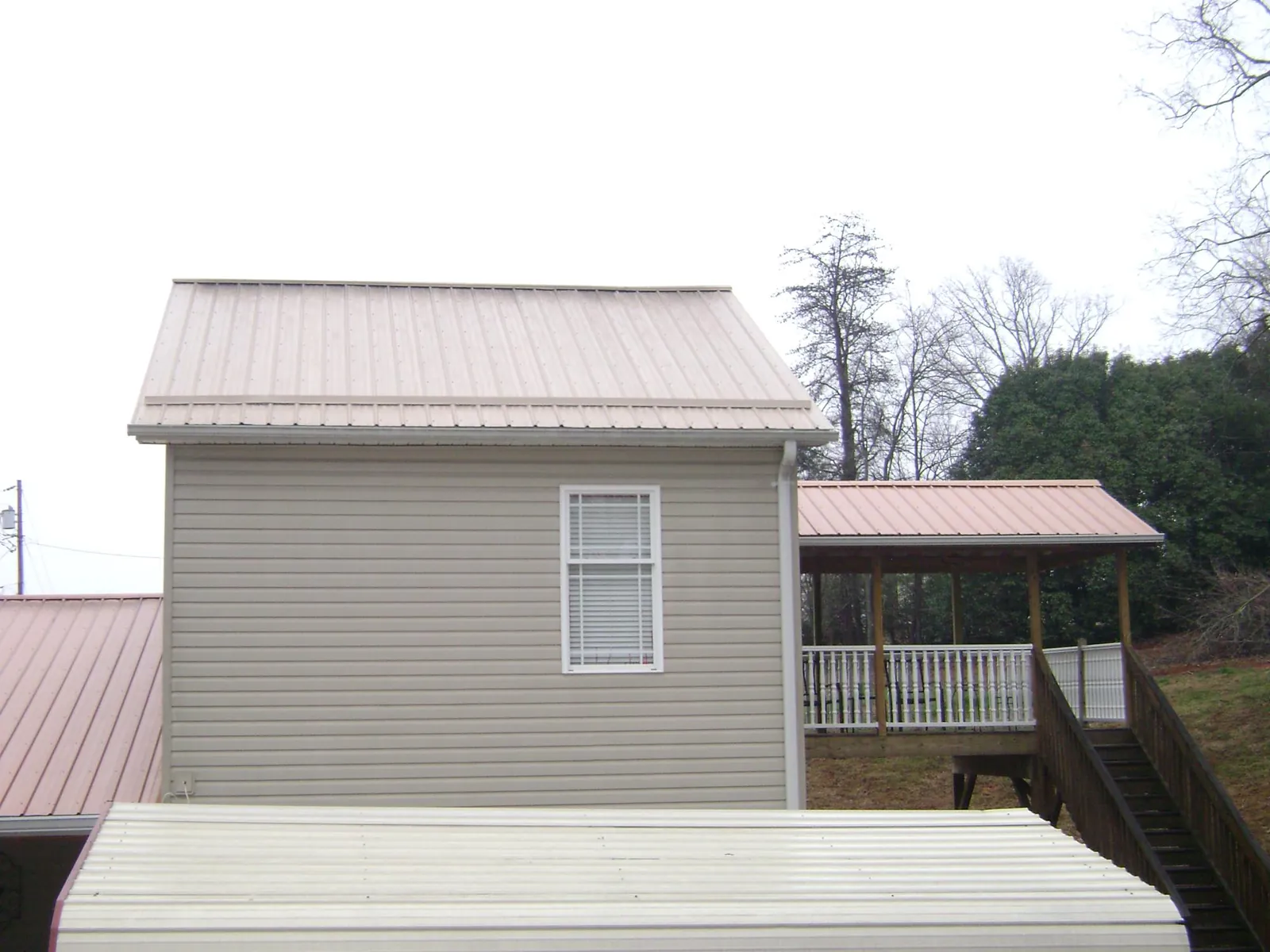 Tan metal roofs on a two story addition and attached porch, from a Roof Replacement job in Bartlett