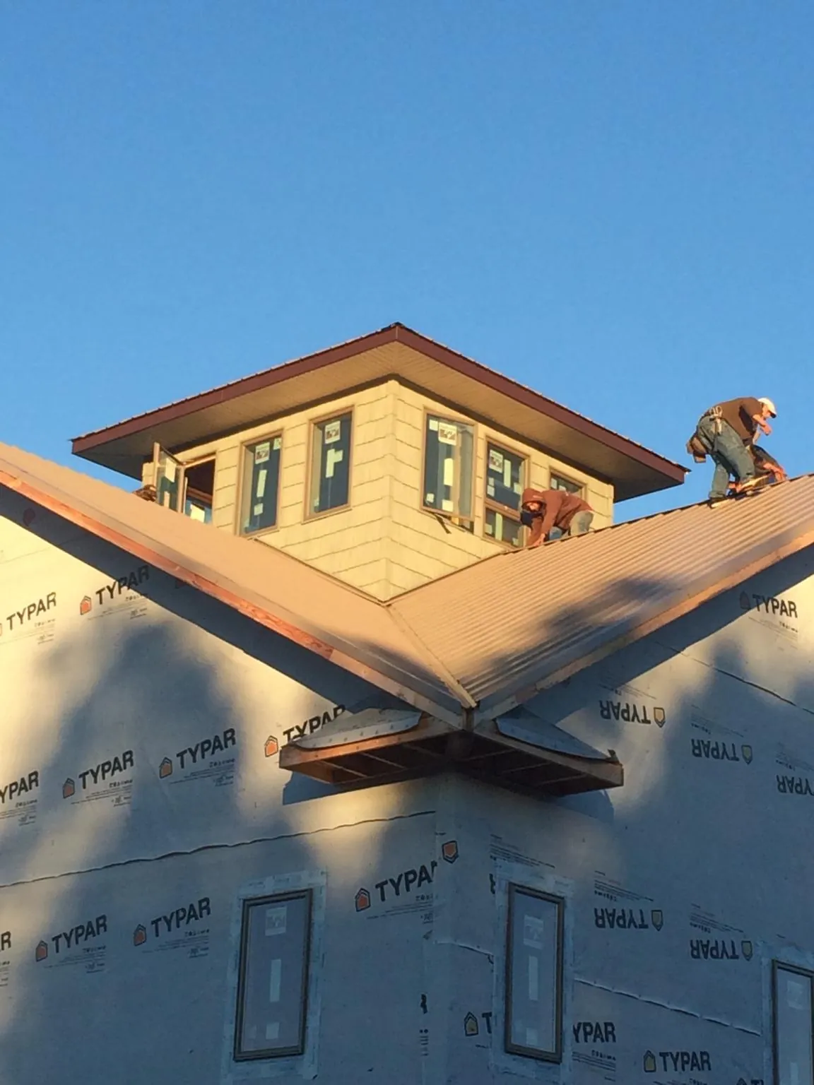 Roofers working around a rooftop cupola on a new metal roof at sunset — Roof Waterproofing in Bartlett by Roofing Brothers